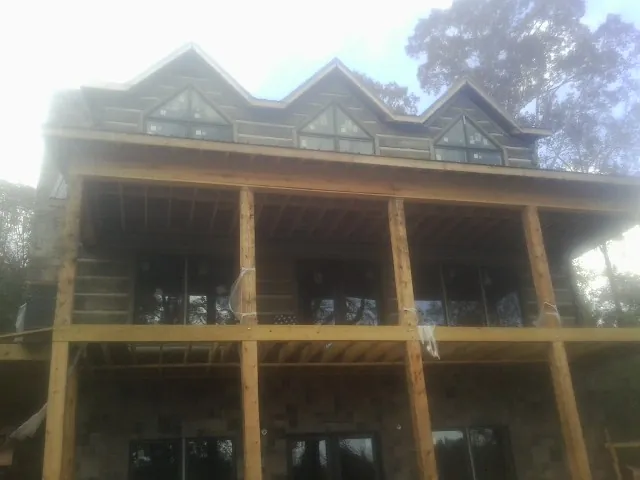 Dormers and porch framing on a large log home under construction — Roof Coating work by our crew in Leesville
