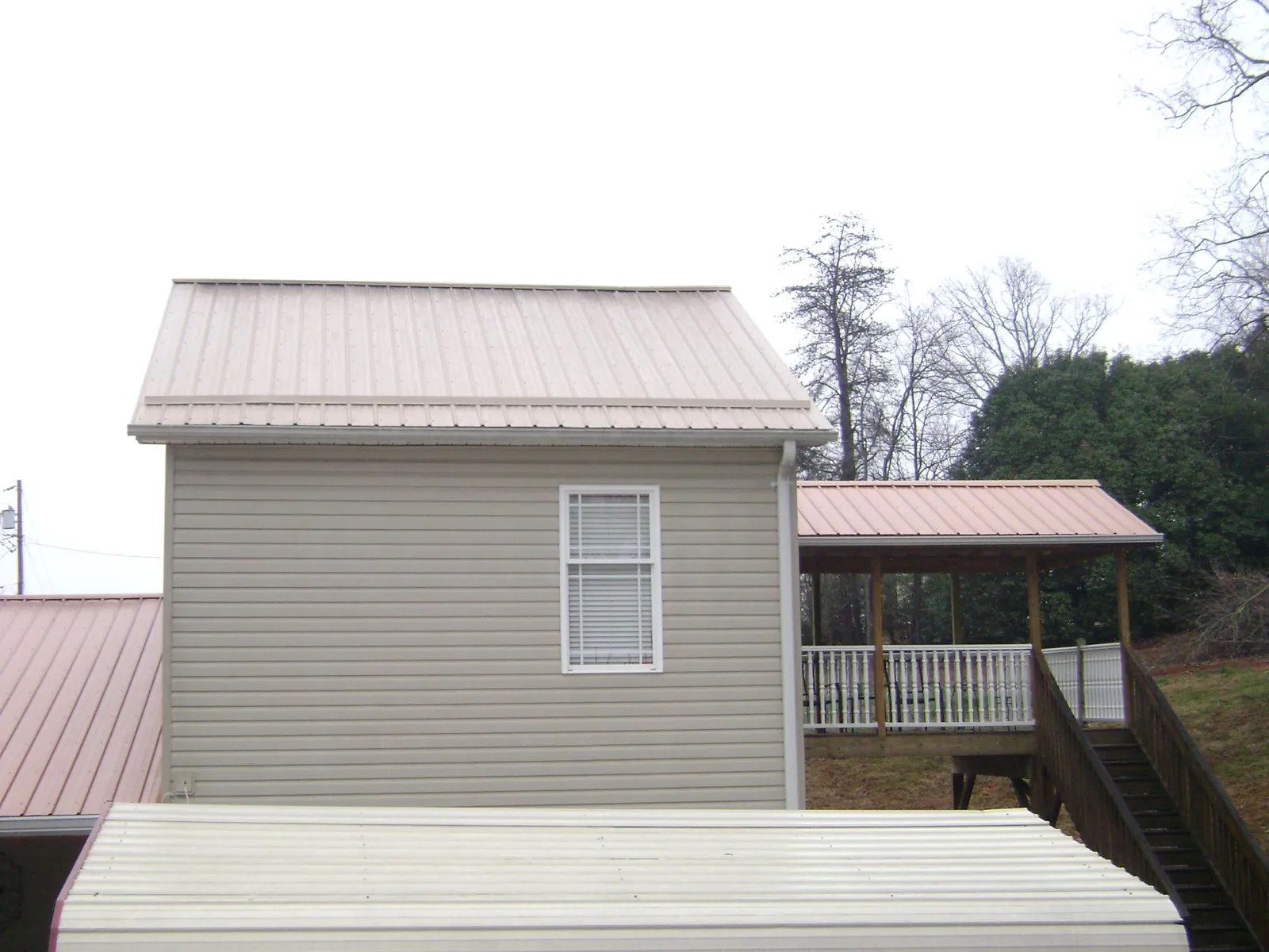 Tan metal roofs on a two story addition and attached porch, from a Roof Replacement job in Leesville